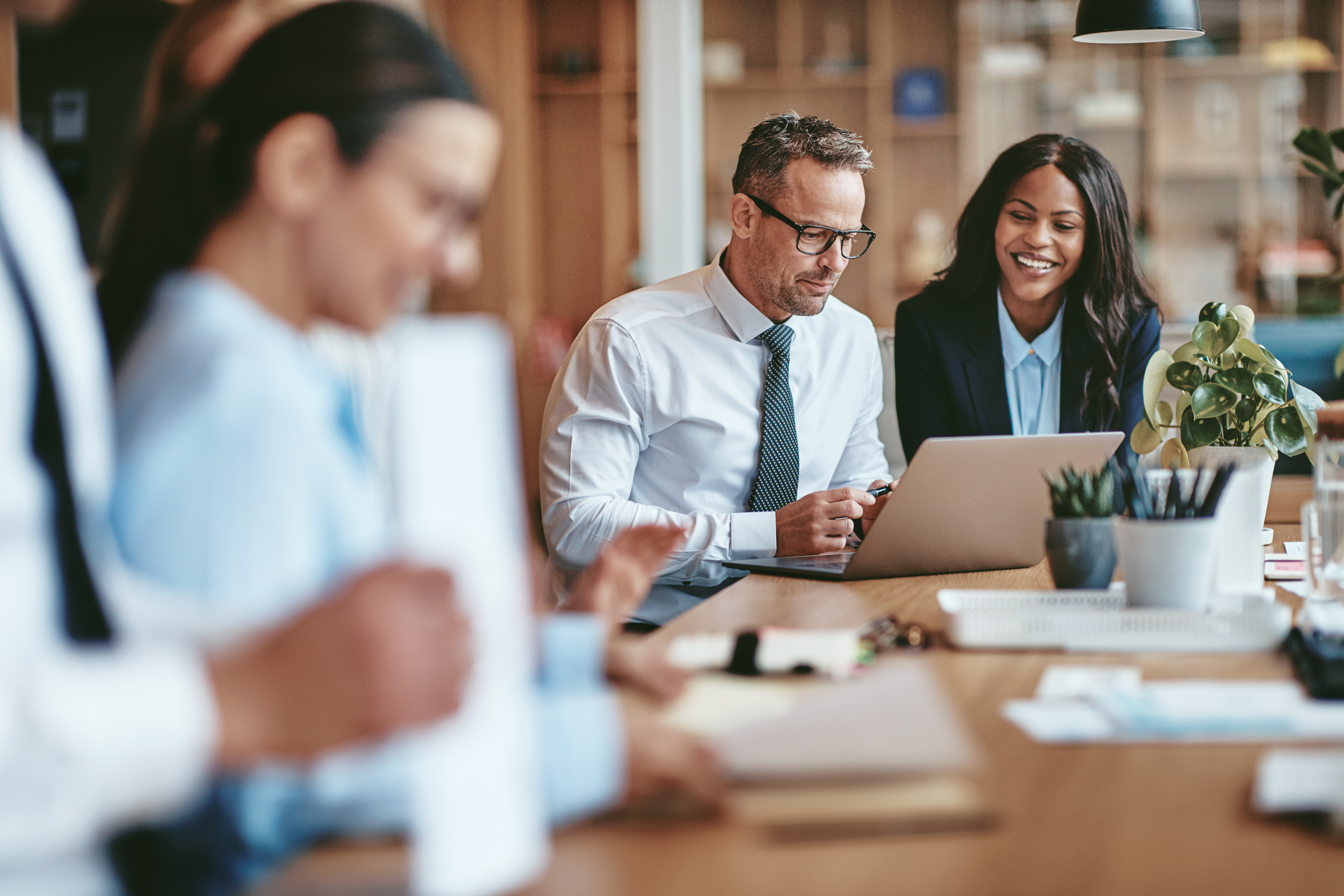 Two smiling diverse businesspeople using a laptop together at work